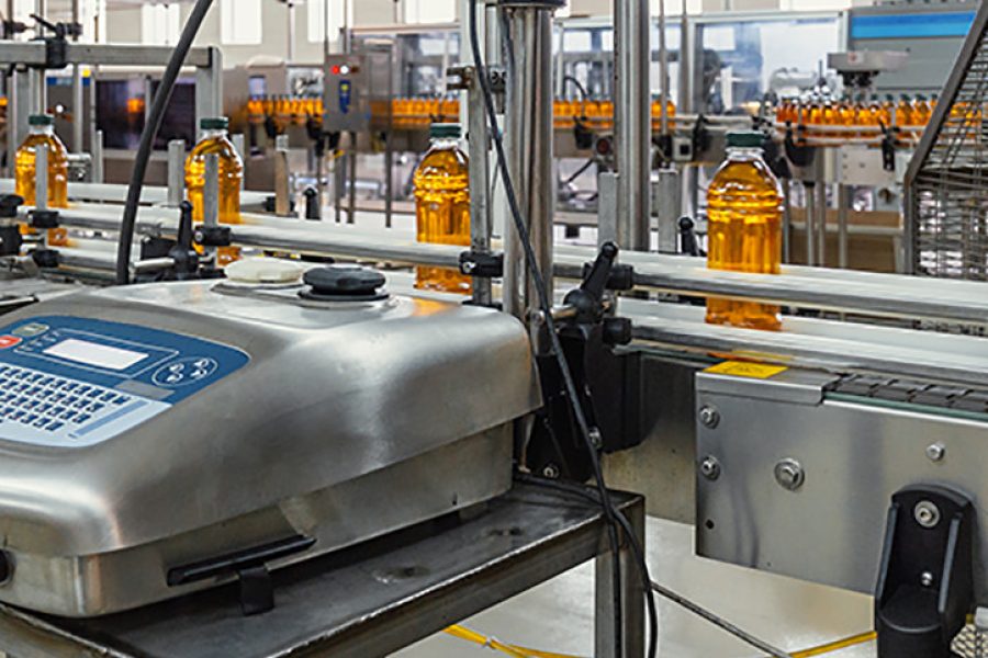 Plastic bottles with juice on automated conveyor line or belt in modern beverage plant or factory production, toned