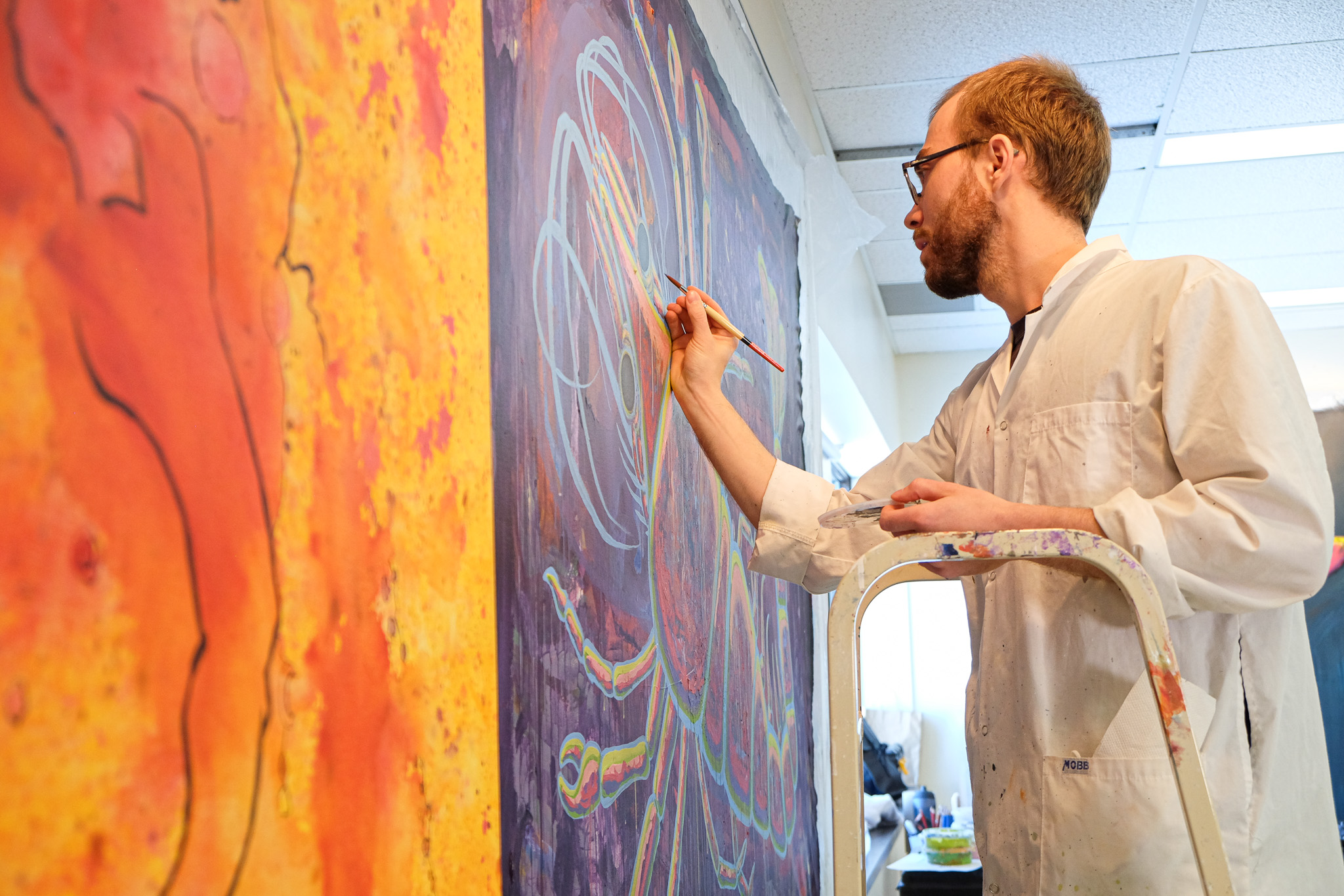 Un étudiant du Cégep de Lévis qui fait une peinture murale.